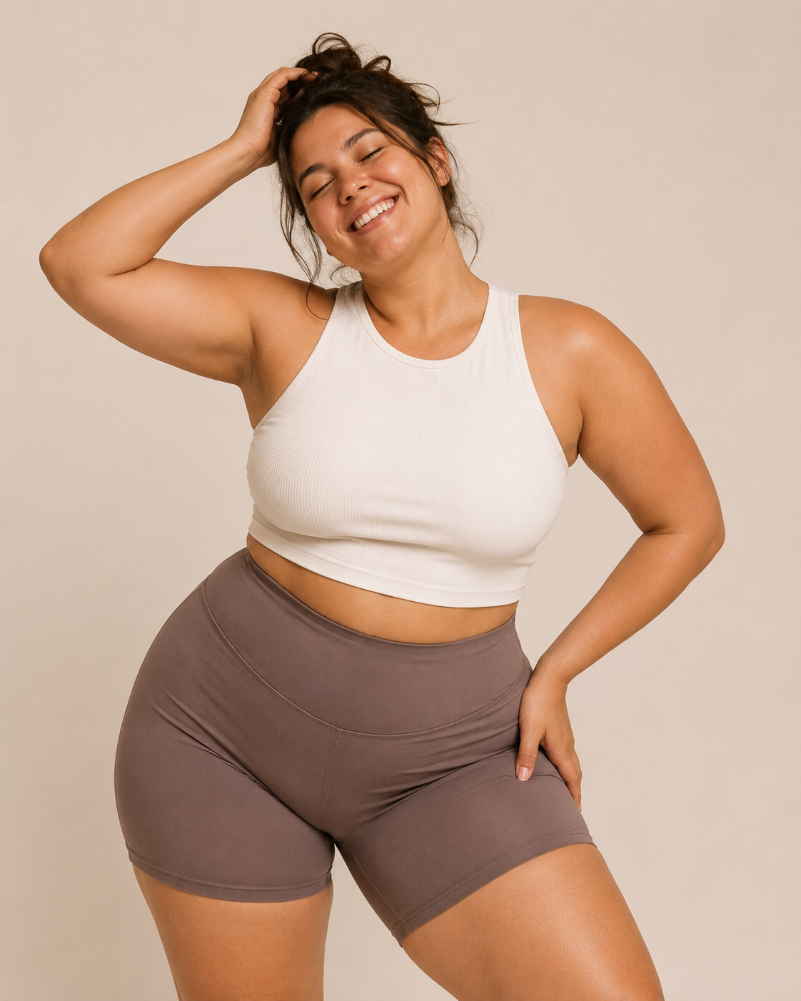 Woman in neutral activewear smiling in a warm studio